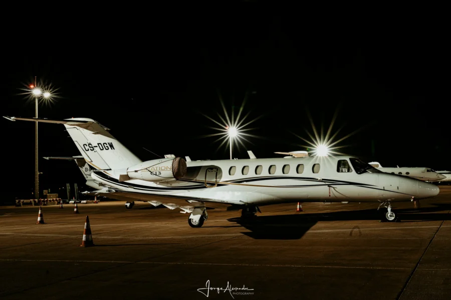 Cessna Citation CJ3 business jet CS-DGW parked at night with its door open under three starburst floodlights.