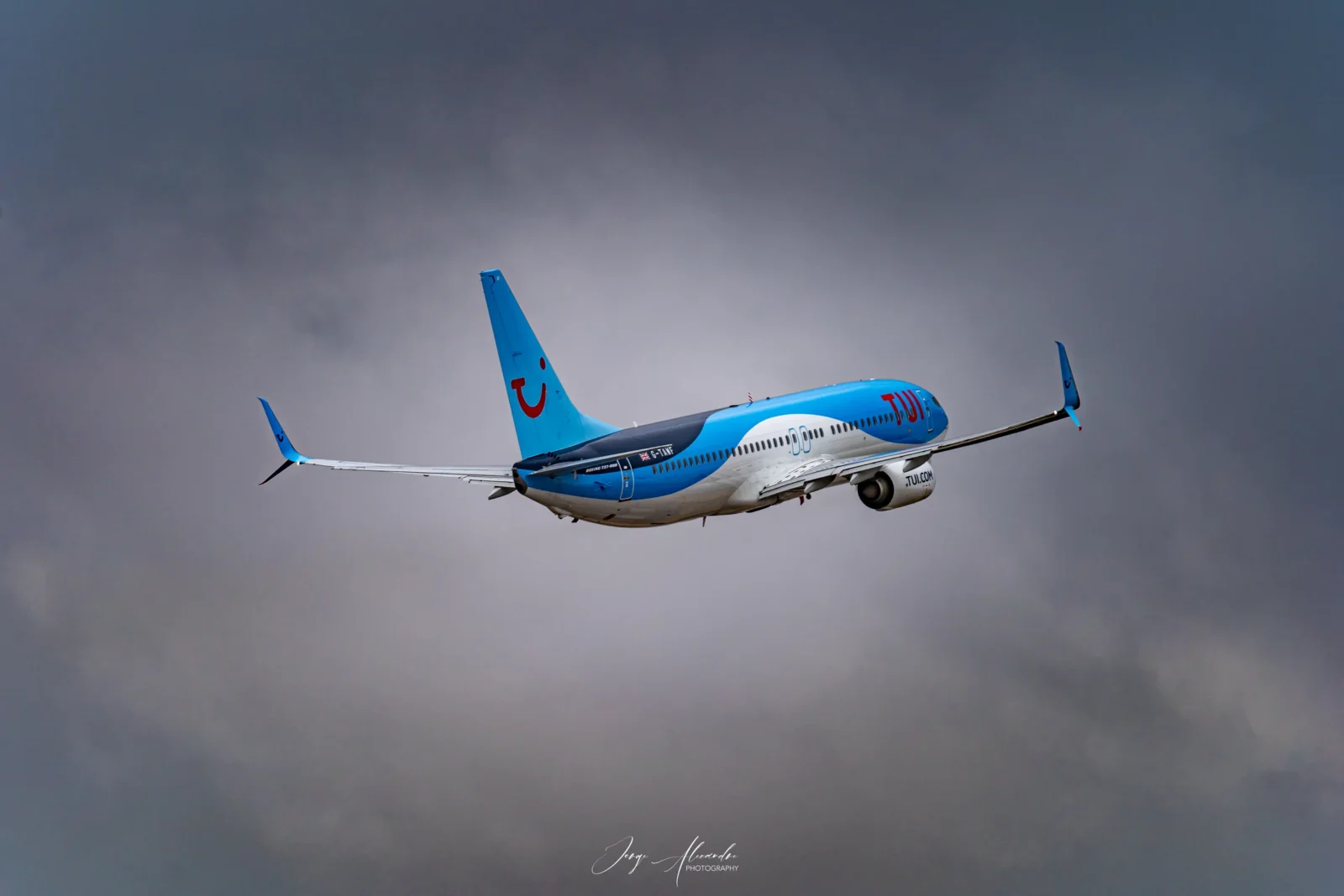 TUI Boeing 737-800 in blue livery climbing away into heavy grey clouds over Faro.
