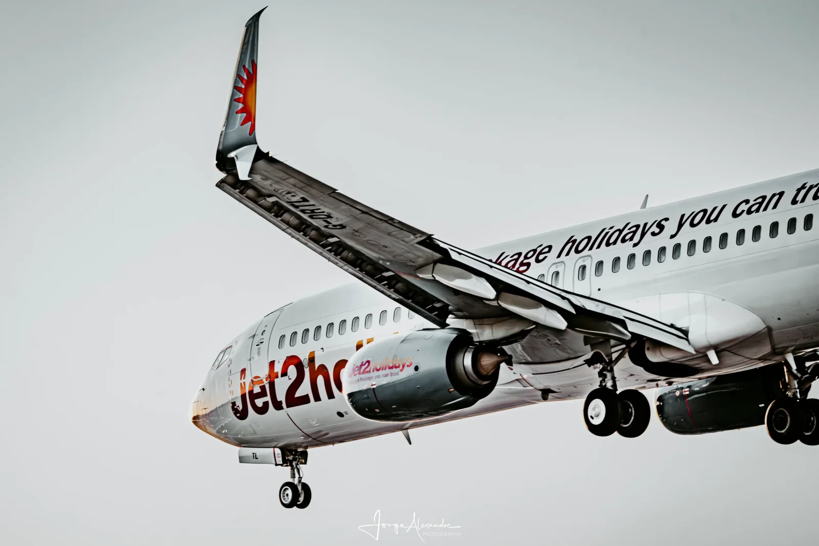 Close view of a Jet2.com Boeing 737 on approach with flaps and landing gear extended against a pale sky.
