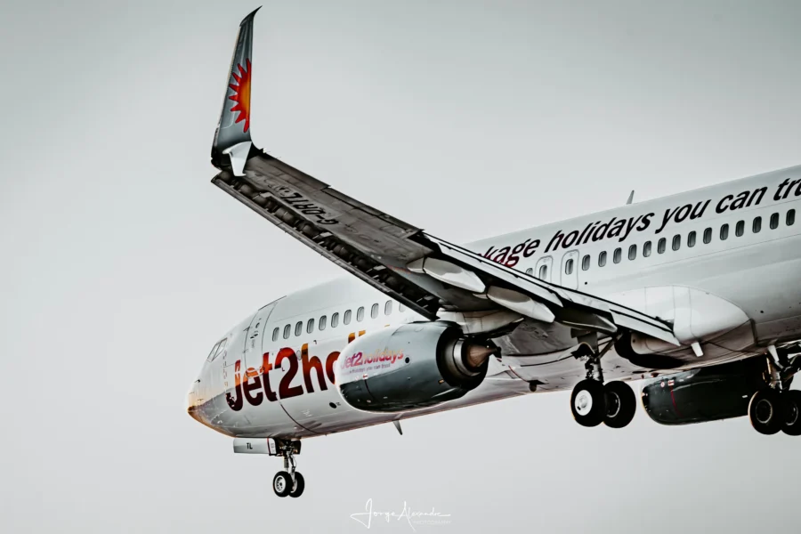 Close view of a Jet2.com Boeing 737 on approach with flaps and landing gear extended against a pale sky.
