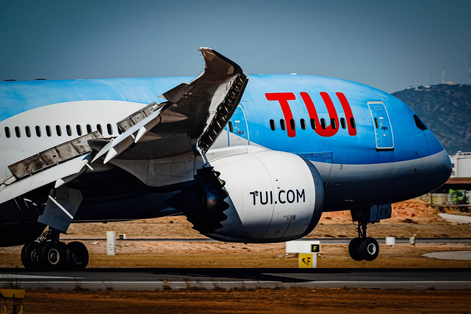TUI Boeing 787 Dreamliner on the runway with flaps and spoilers deployed, blue livery with red TUI lettering.