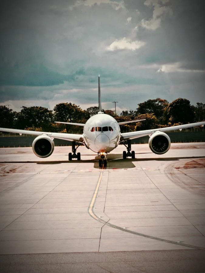 Boeing 787 Dreamliner taxiing head-on along a yellow centreline at Singapore Changi beneath a stormy sky.