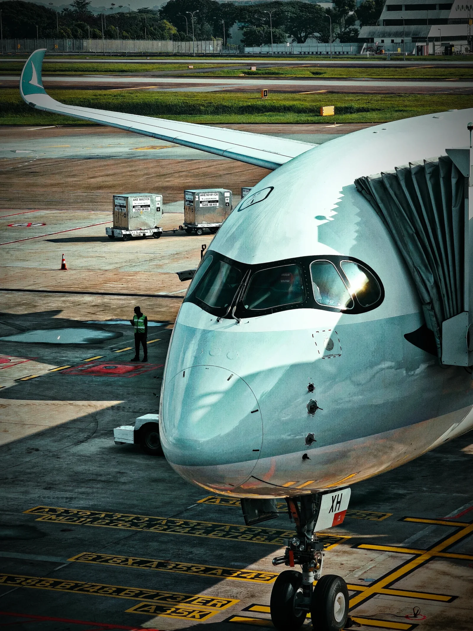 Cathay Pacific Airbus A350 nose and cockpit at a gate at Singapore Changi with its wing curving behind.