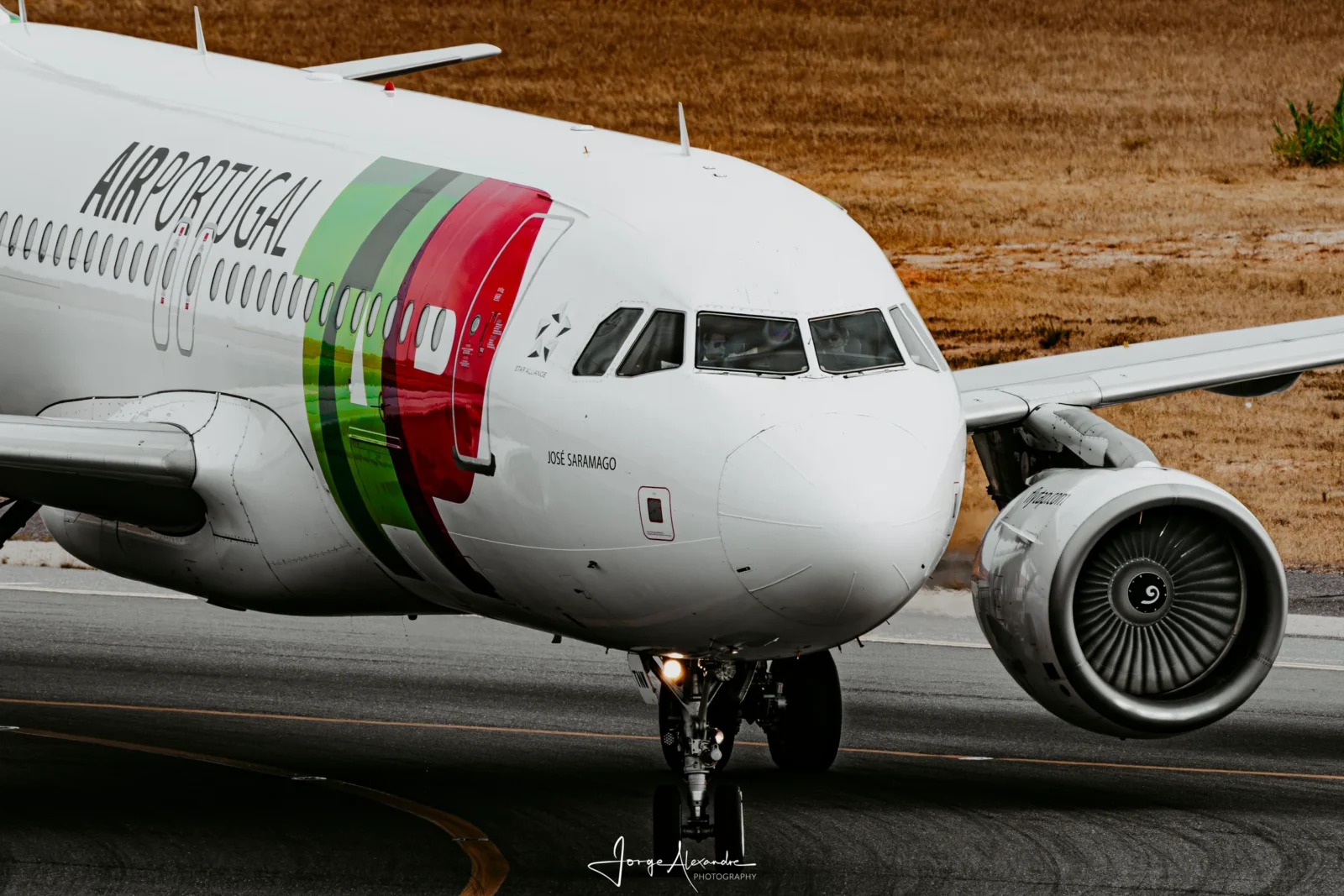 Close view of a TAP Air Portugal Airbus taxiing, with the name José Saramago painted below the cockpit.