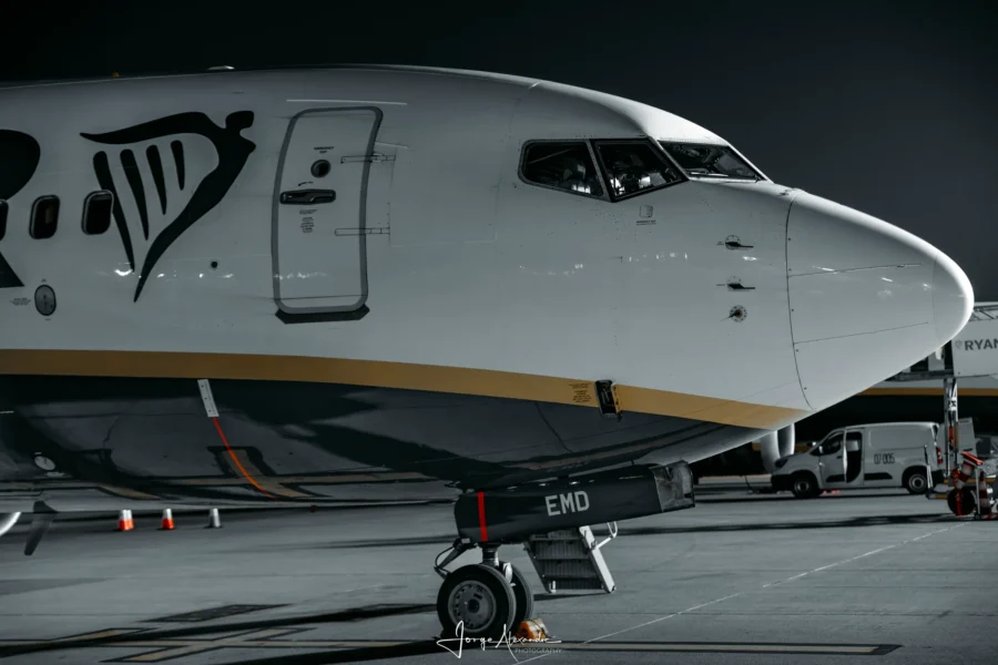 Close view of the nose of Ryanair Boeing 737 EI-EMD at night in a desaturated edit with the gold cheatline retained.