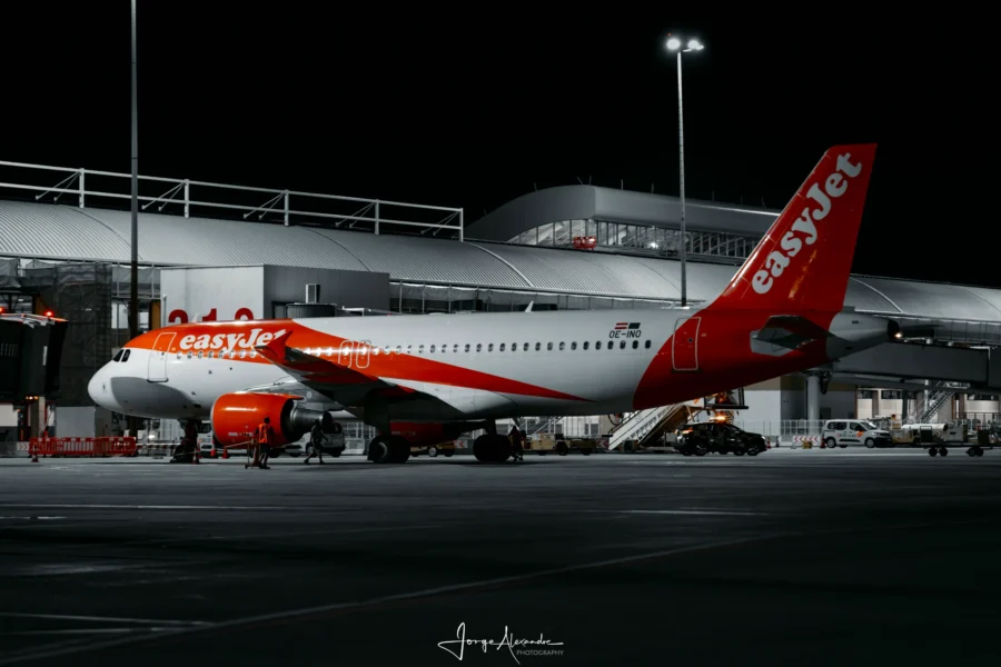 easyJet Airbus with orange tail parked at the terminal at night, in a desaturated edit with the livery in colour.
