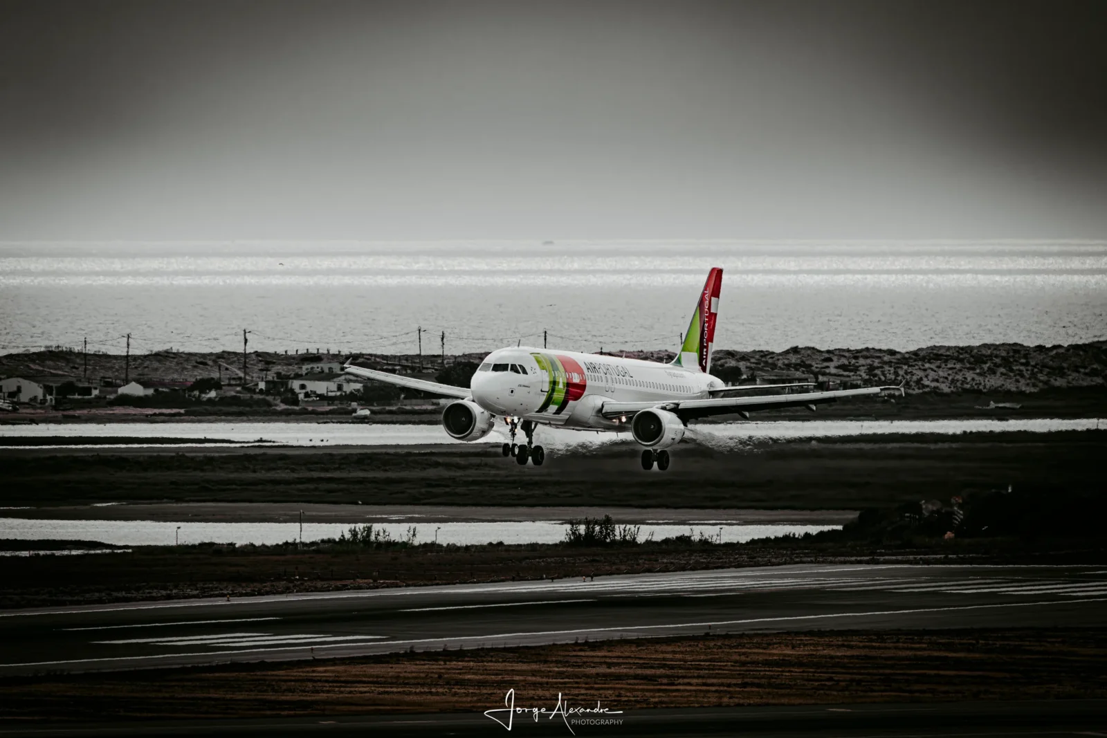 TAP Air Portugal Airbus about to land with a silver lagoon, dunes and sea behind, in a desaturated moody edit.