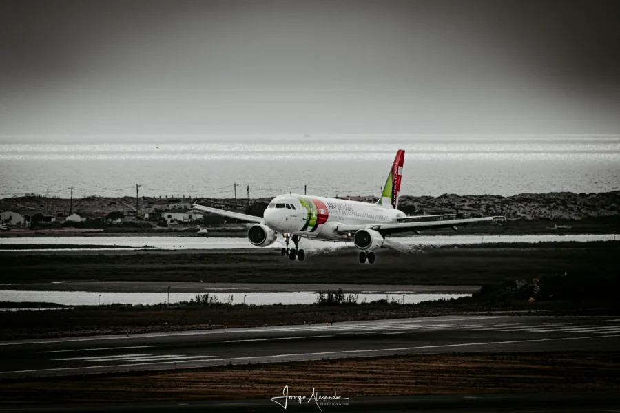 TAP Air Portugal Airbus about to land with a silver lagoon, dunes and sea behind, in a desaturated moody edit.