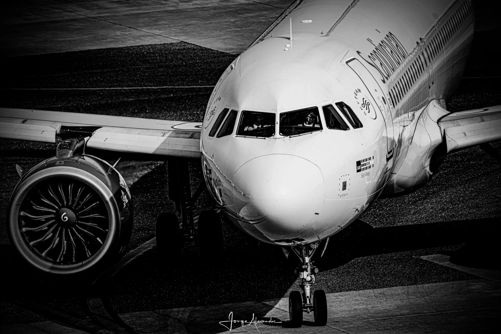 Black and white photograph of an SAS Airbus nose and engine turning towards the camera on the taxiway.