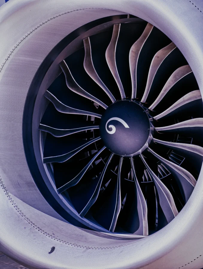 Close-up of a turbofan engine's fan blades and spiral-marked spinner in cool silver and indigo tones.