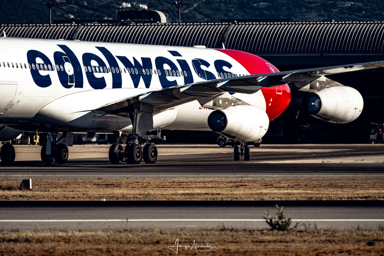 Edelweiss Airbus A340 rolling along the runway, showing two of its four engines and large airline lettering.