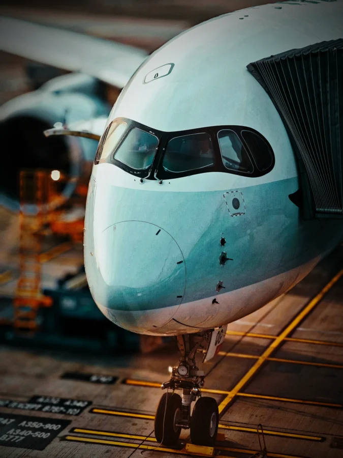 Close portrait of an Airbus A350 nose and cockpit at a gate at Hong Kong International with warm blurred lights.