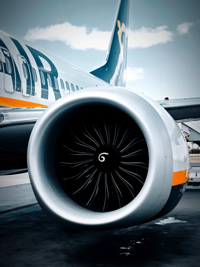 Close-up of a jet engine nacelle and fan with a spiral spinner beneath large airline lettering and a blue sky.