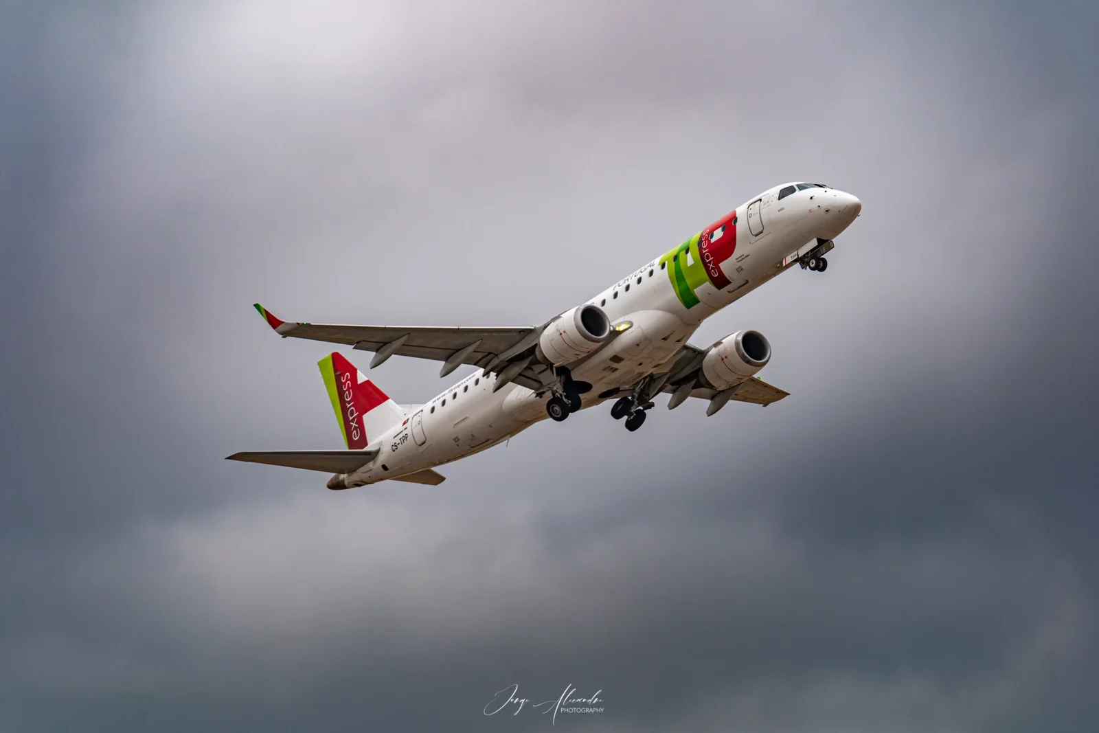 TAP Express Embraer regional jet named Viseu climbing out of Faro under grey clouds.