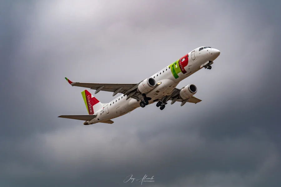TAP Express Embraer regional jet named Viseu climbing out of Faro under grey clouds.